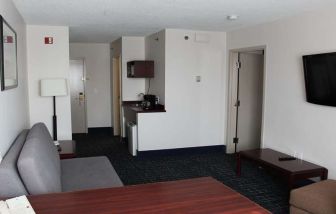 Family room with TV screen and sofa at Riviera Plaza And Conference Centre Calgary Airport.