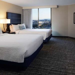 Twin room with TV screen and sofa at Embassy Suites By Hilton LAX Airport North.