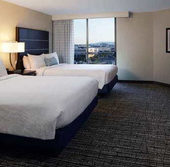 Twin room with TV screen and sofa at Embassy Suites By Hilton LAX Airport North.