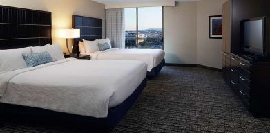 Twin room with TV screen and sofa at Embassy Suites By Hilton LAX Airport North.