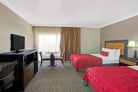 Twin room with desk, TV screen and table at Ramada Los Angeles Downtown West.