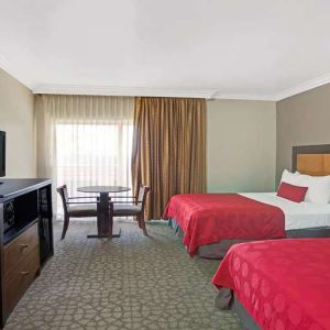 Twin room with desk, TV screen and table at Ramada Los Angeles Downtown West.