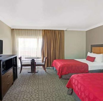 Twin room with desk, TV screen and table at Ramada Los Angeles Downtown West.