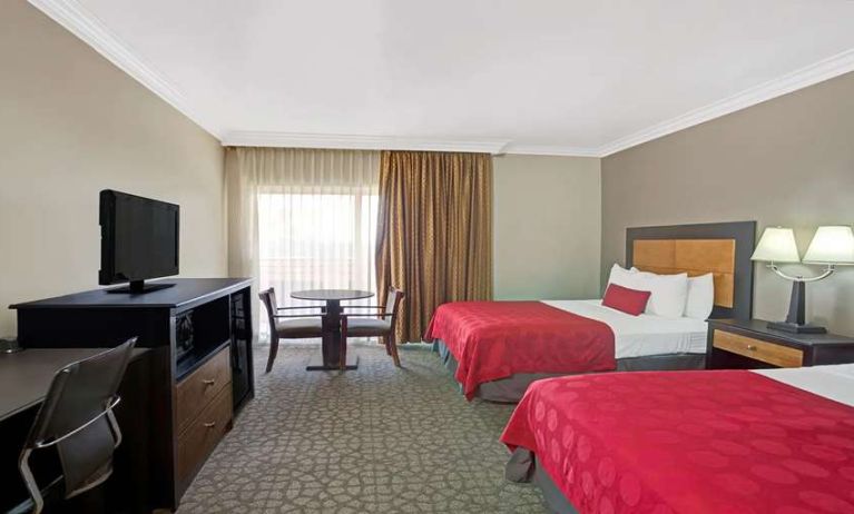 Twin room with desk, TV screen and table at Ramada Los Angeles Downtown West.