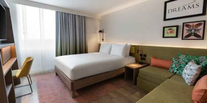 Queen bedroom with corner sofa at the Hampton by Hilton Istanbul Arnavutkoy.