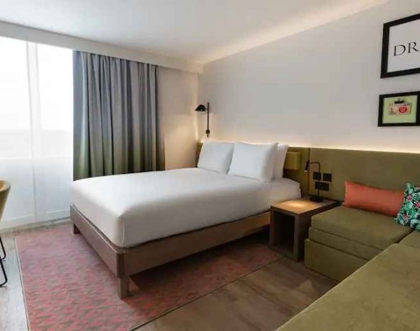Queen bedroom with corner sofa at the Hampton by Hilton Istanbul Arnavutkoy.