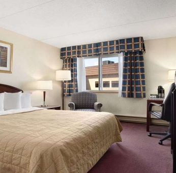 Hotel bedroom with TV screen and desk at Travelodge Ottawa East.