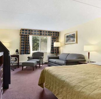 King bedroom with TV screen and workstation at Travelodge Ottawa East.