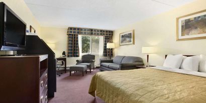 King bedroom with TV screen and workstation at Travelodge Ottawa East.