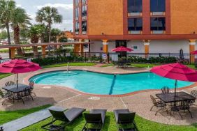 Large outdoor pool with seating area and sun umbrellas at Quality Inn Pasadena.