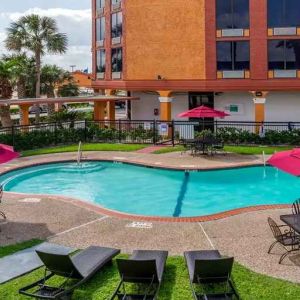 Large outdoor pool with seating area and sun umbrellas at Quality Inn Pasadena.