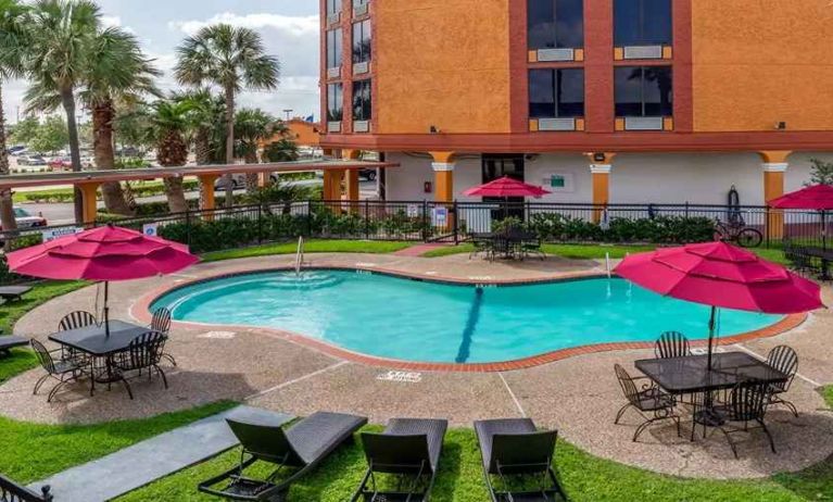 Large outdoor pool with seating area and sun umbrellas at Quality Inn Pasadena.