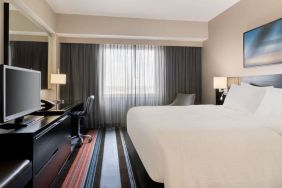 Spacious delux king room with TV, business desk, and couch at Courtyard By Marriott New York JFK Airport.