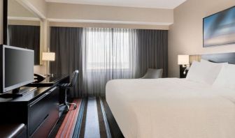 Spacious delux king room with TV, business desk, and couch at Courtyard By Marriott New York JFK Airport.