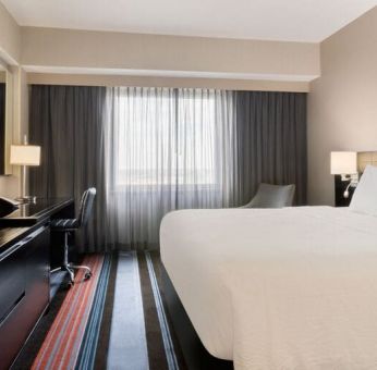 Spacious delux king room with TV, business desk, and couch at Courtyard By Marriott New York JFK Airport.