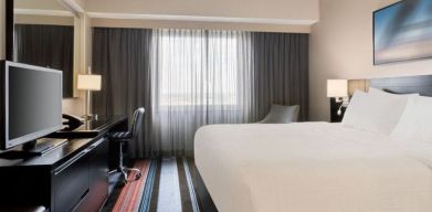 Spacious delux king room with TV, business desk, and couch at Courtyard By Marriott New York JFK Airport.