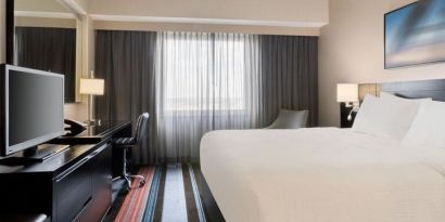 Spacious delux king room with TV, business desk, and couch at Courtyard By Marriott New York JFK Airport.