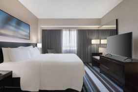 Comfortable king room with TV and couch at Courtyard By Marriott New York JFK Airport.