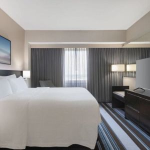 Comfortable king room with TV and couch at Courtyard By Marriott New York JFK Airport.