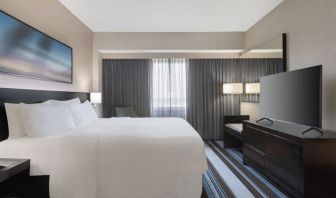 Comfortable king room with TV and couch at Courtyard By Marriott New York JFK Airport.