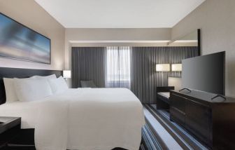 Comfortable king room with TV and couch at Courtyard By Marriott New York JFK Airport.