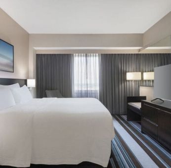 Comfortable king room with TV and couch at Courtyard By Marriott New York JFK Airport.