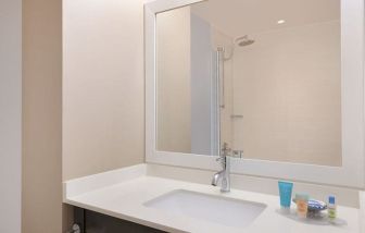 Spacious guest bathroom with shower at Courtyard By Marriott New York JFK Airport.