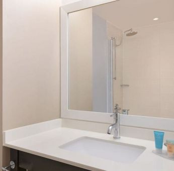 Spacious guest bathroom with shower at Courtyard By Marriott New York JFK Airport.