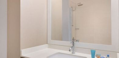 Spacious guest bathroom with shower at Courtyard By Marriott New York JFK Airport.