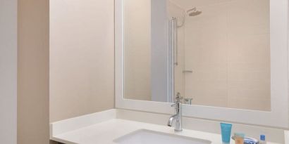 Spacious guest bathroom with shower at Courtyard By Marriott New York JFK Airport.