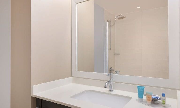 Spacious guest bathroom with shower at Courtyard By Marriott New York JFK Airport.