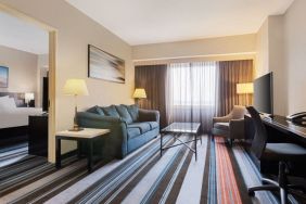 Luxurious king suite with TV, work desk, and couch at Courtyard By Marriott New York JFK Airport.