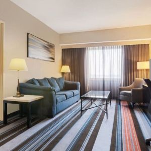 Luxurious king suite with TV, work desk, and couch at Courtyard By Marriott New York JFK Airport.