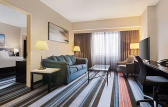 Luxurious king suite with TV, work desk, and couch at Courtyard By Marriott New York JFK Airport.