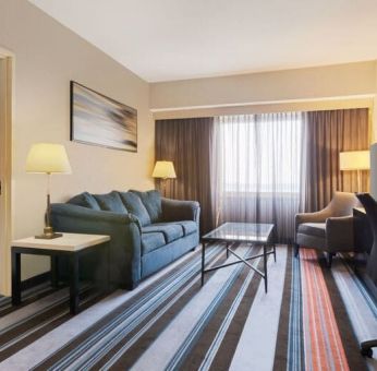 Luxurious king suite with TV, work desk, and couch at Courtyard By Marriott New York JFK Airport.