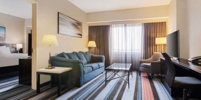 Luxurious king suite with TV, work desk, and couch at Courtyard By Marriott New York JFK Airport.