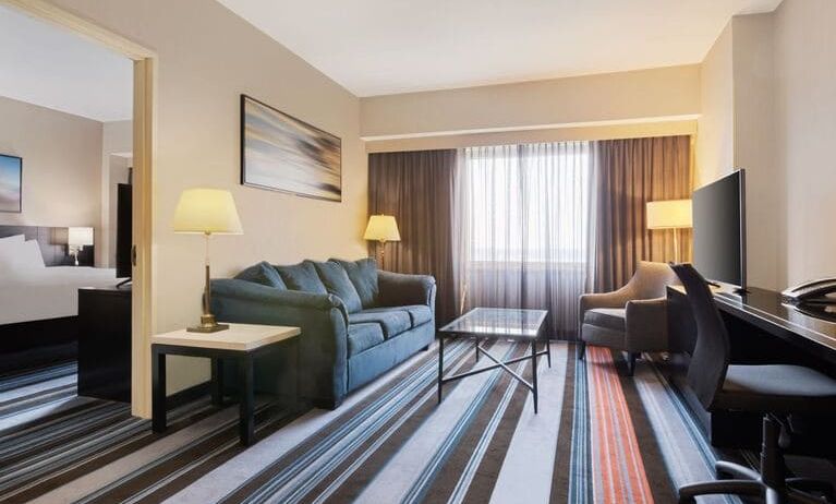 Luxurious king suite with TV, work desk, and couch at Courtyard By Marriott New York JFK Airport.