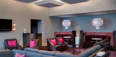 Comfortable couches in open-plan setting ideal for coworking at Courtyard By Marriott New York JFK Airport.