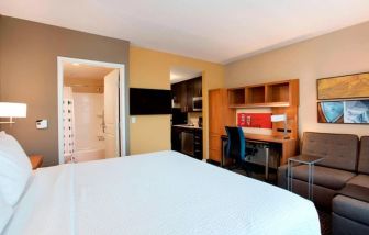 Lovely king bedroom with business desk, TV, and lounge area at TownePlace Suites Orlando at FLAMINGO CROSSINGS.