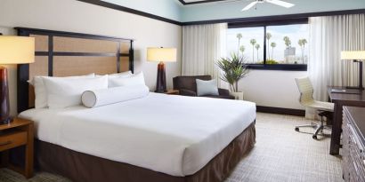 Comfortable king bedroom with couch and work station at The Ambrose Hotel Santa Monica.