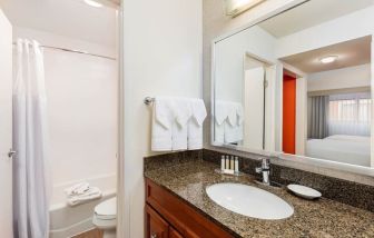 Private guest bathroom with shower and bath at Clementine Hotel & Suites Anaheim.