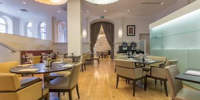 Tables and chairs in the airy, well-lit hotel restaurant.