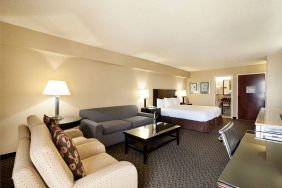 Junior suite of the Radisson Hotel JFK Airport, with bed and pair of sofas, plus small table.