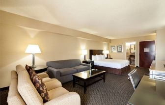 Junior suite of the Radisson Hotel JFK Airport, with bed and pair of sofas, plus small table.