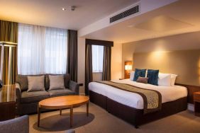 Wide view of the Thistle Trafalgar Square executive king room, featuring large bed, sofa, and TV.