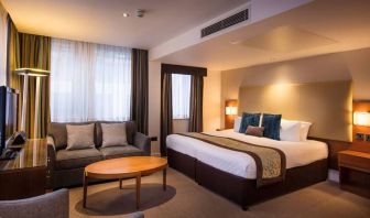 Wide view of the Thistle Trafalgar Square executive king room, featuring large bed, sofa, and TV.