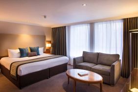 Wide view of the junior suite double room, with small sofa, coffee table, and spacious bed.