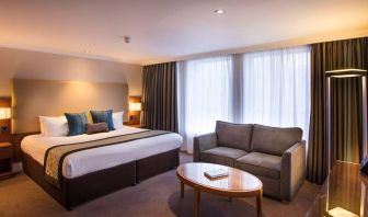 Wide view of the junior suite double room, with small sofa, coffee table, and spacious bed.