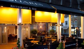 A nocturnal exterior view of the Thistle Trafalgar Square hotel including outdoor seating.