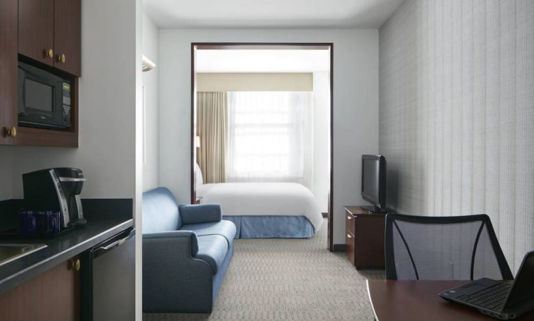 Guest room in the Club Quarters Hotel Wacker At Michigan, with kitchenette, sofa, bed, and window.